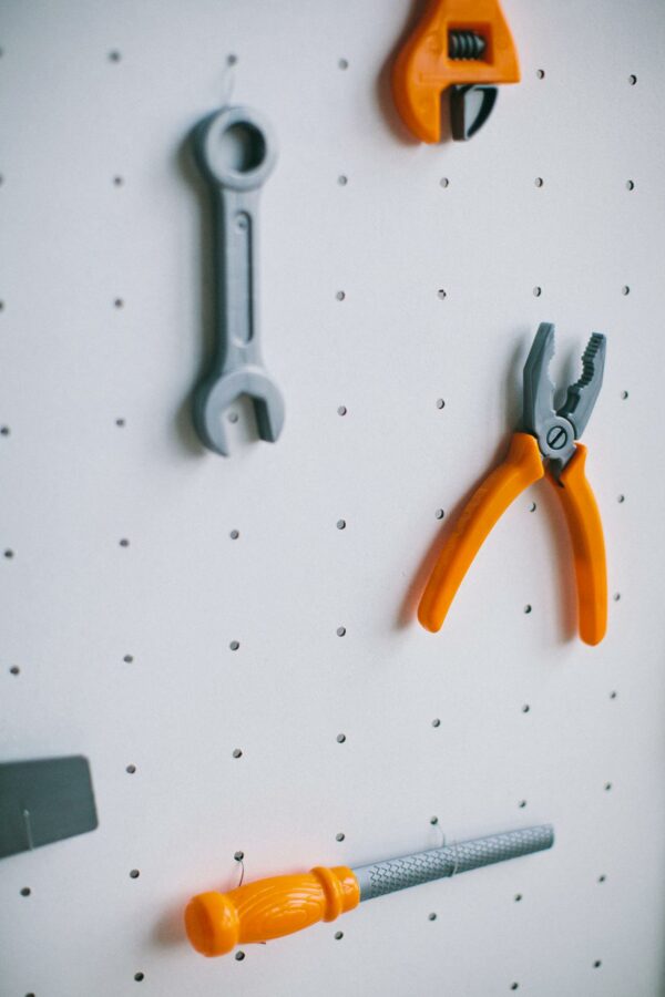 Pegboard with tools including pliers, wrench, and file for organized storage.