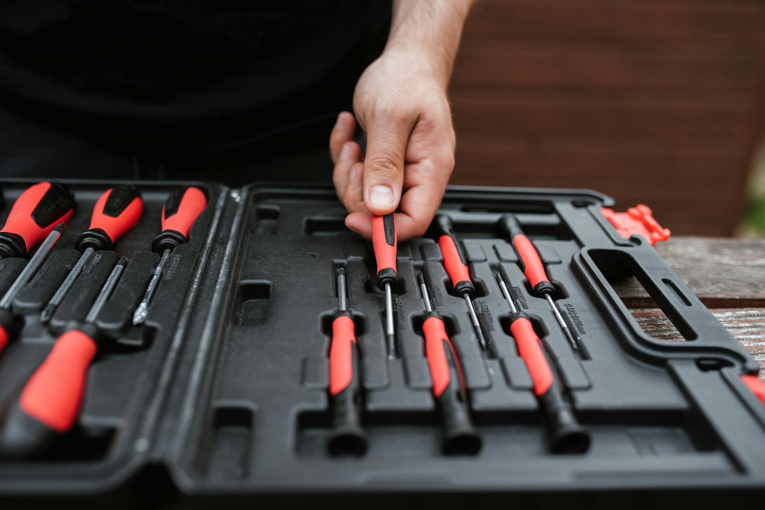 Person choosing a screwdriver from a toolkit during a maintenance task.
